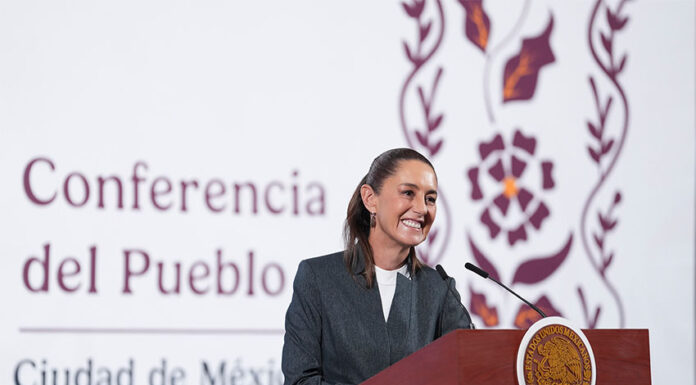 President Claudia Sheinbaum stands at a podium smiling