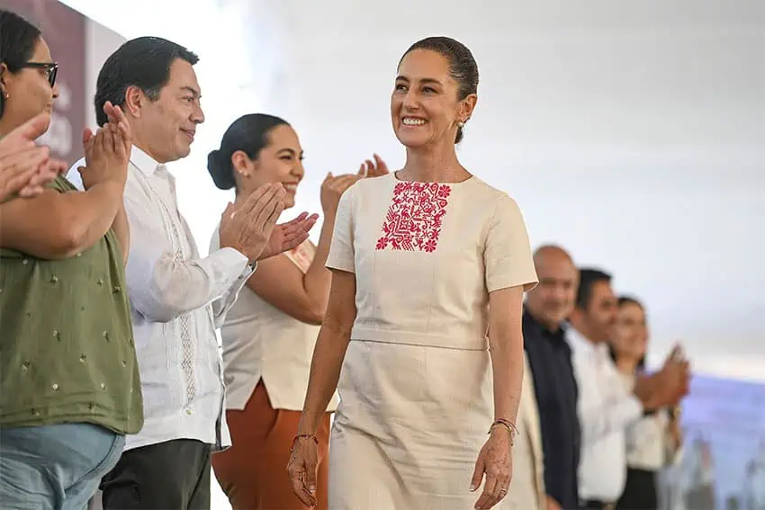 President Sheinbaum, wearing a white huipil-style dress, walks past supporters