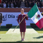 President Sheinbaum carries a Mexican flag, flanked by military