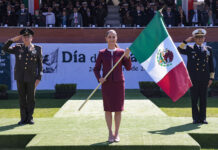 President Sheinbaum carries a Mexican flag, flanked by military