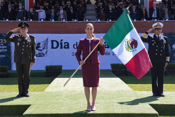 President Sheinbaum carries a Mexican flag, flanked by military