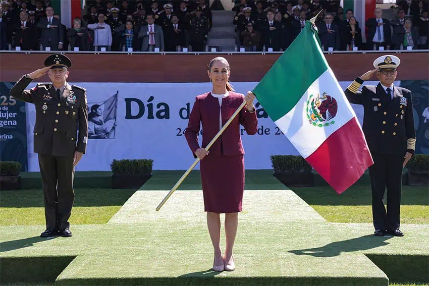 El presidente Sheinbaum lleva una bandera mexicana, flanqueada por militares, que representa el orgullo nacional en México