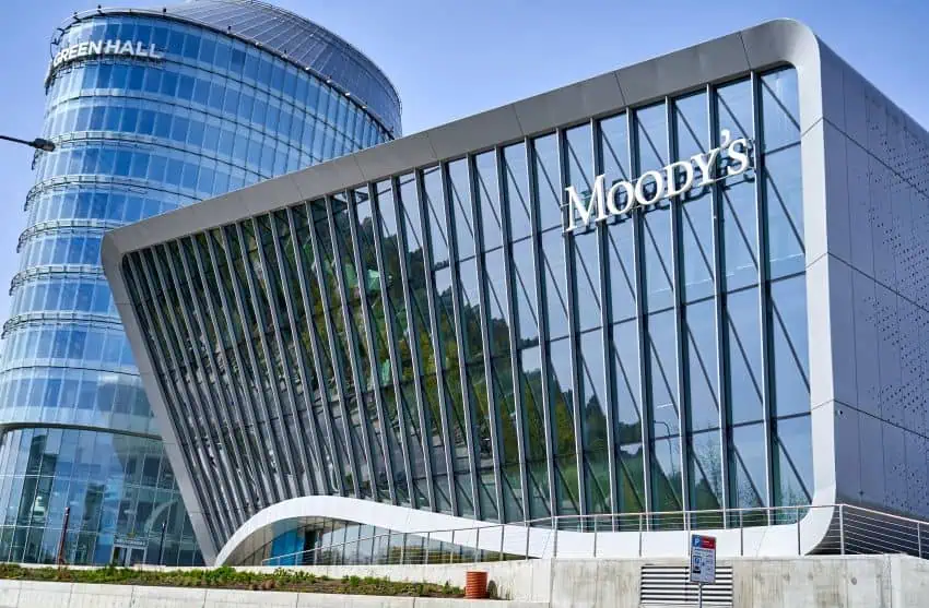 Moody's credit ratings firm's building, which is shaped like a rectangle with a long curve at the base and built with blue skyscraper glass on the facade.