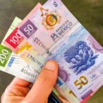 A hand holding three Mexican currency bills: the 200 pesos bill, the 100 peso bill and the 50 peso bills
