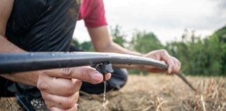A close-up shot shows a person adjusting an irrigation line in a field to reduce agricultural water waste