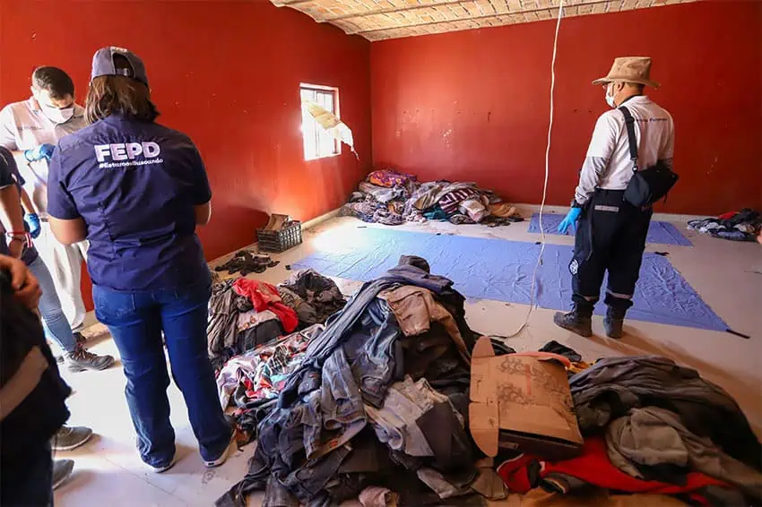 People with uniforms reading FEPD stand next to clean tarps and piles of old clothes in a red room