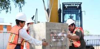 Officials in construction vests and hard hats place a block of cement to celebrate a new phase in Mexico's affordable housing plan