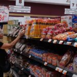 A woman takes a product off a grocery store shelf