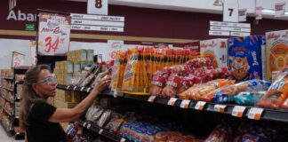 A woman takes a product off a grocery store shelf
