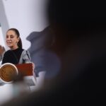 Claudia Sheinbaum stands at the presidential podium during her daily press conference, talking about US tariffs