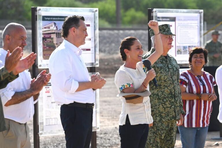 President Sheinbaum raises a fist while standing next to a military engineer