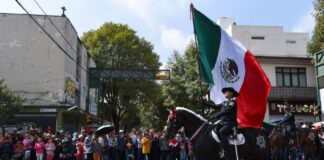 A military rider on horseback bears a Mexico flag in a parade