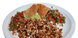 A white plate with escamoles at the center, with chips, guacamole and salsaon the side