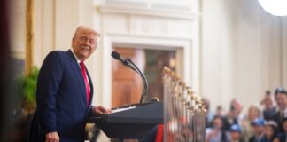 U.S. President Donald Trump smiles from behind a podium