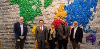 Leaders from LEGO and Nuevo León pose in front of a mural of a world map made of LEGOS