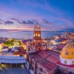 Skyline of Puerto Vallarta, with the Pacific Ocean in the background and buildings with Arabic-style domes in the foreground.