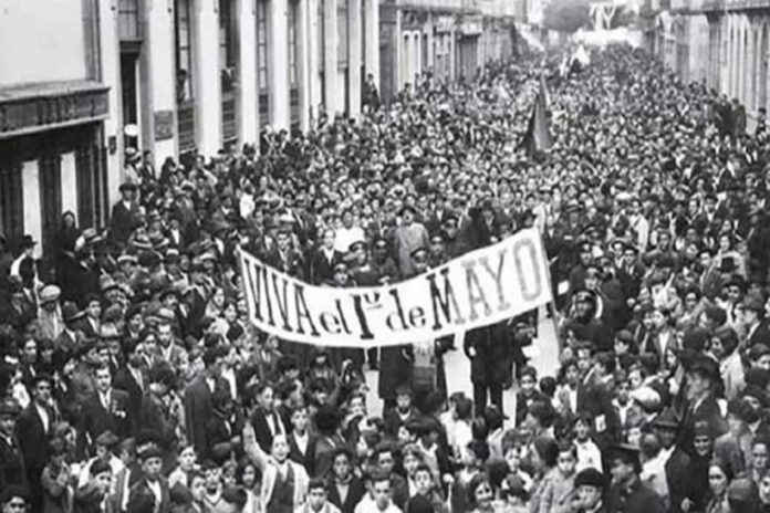 Black and white photo of crowds filling the streets of Mexico City in 1944 carrying a large banner saying 
