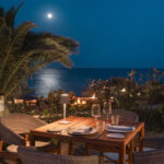 A restaurant table set for a candlelit dinner but the ocean