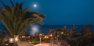 A restaurant table set for a candlelit dinner but the ocean