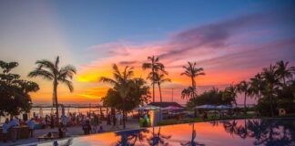 Sunset skies at a beach club in Punta Mita, where elegant tents and umbrellas shade guests by the ocean.