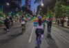 Bicycle riders biking at night in Mexico City wearing inflatable rainbow-colored angel wings