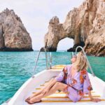 A woman sits on a boat in from of Los Cabos' Los Arcos