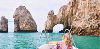 A woman sits on a boat in from of Los Cabos' Los Arcos