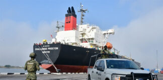 A Navy seaman stands guard in front of a tanker ship