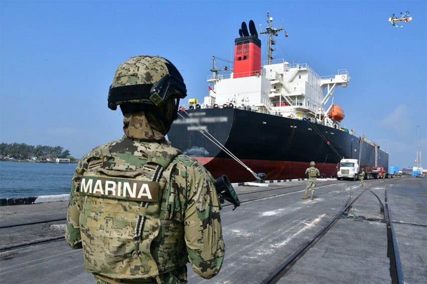 A person in green fatigues stamped with the word "Marina" stands guard in front of a ocean tanker that was used for fuel smuggling