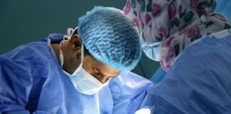 Surgeons lean over their patient as they work