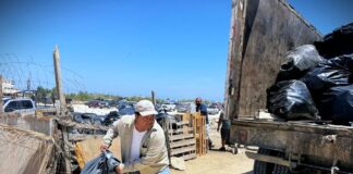 Sanitation worker hoists garbage bags into truck in Los Cabos