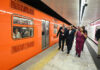 President Sheinbaum, CDMX Mayor Clara Brugada and other officials walk along a Mexico City Metro platform next to an orange train