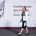 President Sheinbaum walks onstage at her morning press conference, in front of a banner reading "Conferencia del Pueblo, Ciudad de Mexico"