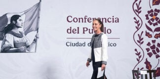 President Sheinbaum walks onstage at her morning press conference, in front of a banner reading "Conferencia del Pueblo, Ciudad de Mexico"
