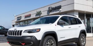 A white Jeep with the logos of Dodge, Ram and Jeep - all Stellantis brands - in the background