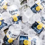 Cans of Cororna Extra beer lying on a bed of large ice cubes