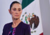 Claudia Sheinbaum with a serious expression and a Mexican flag