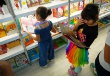 Young children looking at books at a book fair.