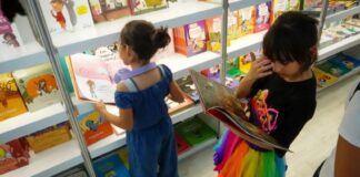 Young children looking at books at a book fair.