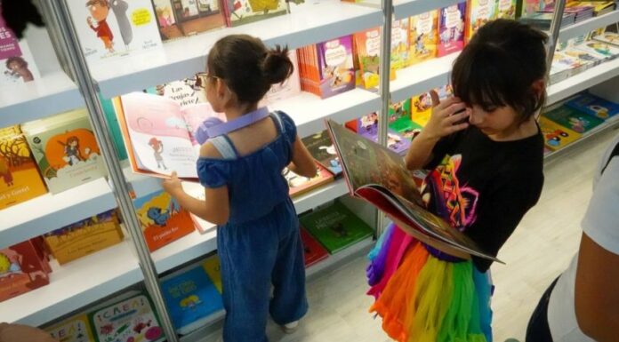 Young children looking at books at a book fair.