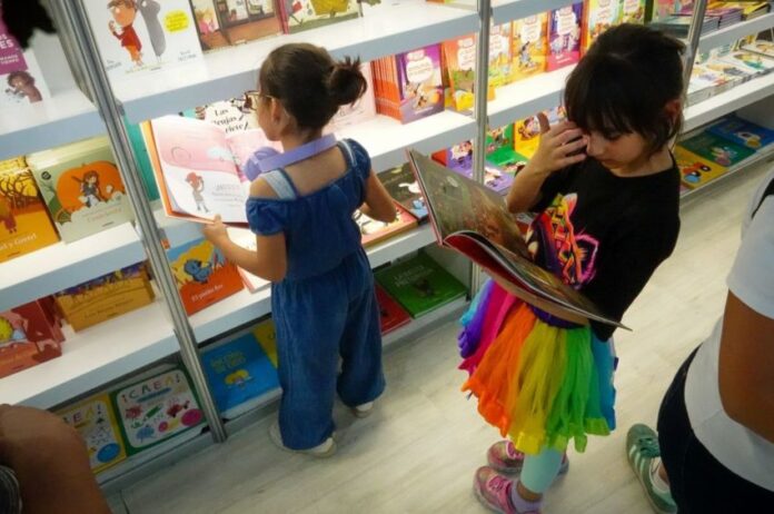 Young children looking at books at a book fair.