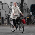 A man wearing a face mask rides a bicycle down a city street