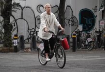 A man wearing a face mask rides a bicycle down a city street