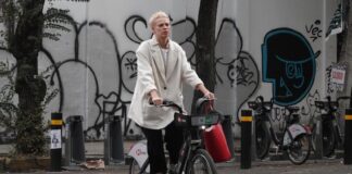 A man wearing a face mask rides a bicycle down a city street
