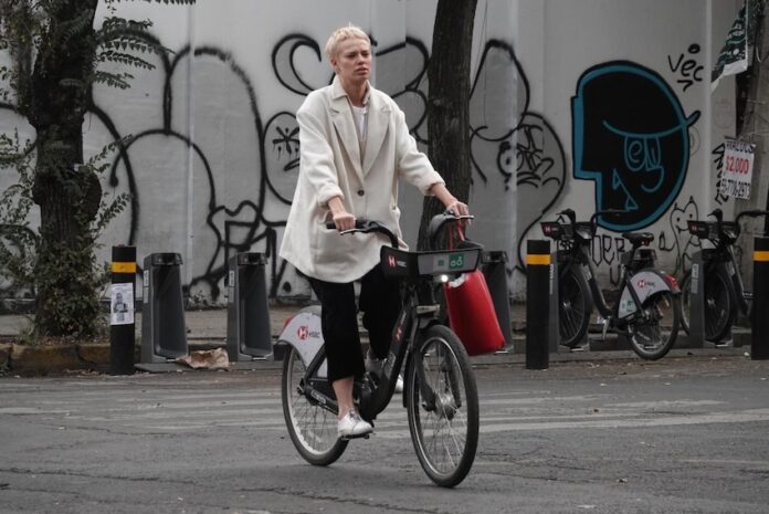 A man wearing a face mask rides a bicycle down a city street