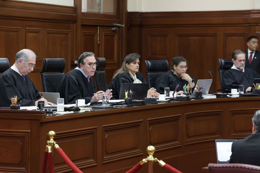 Five members of Mexico's Supreme Court in their black robes sitting at the official bench of the Court conducting a session.