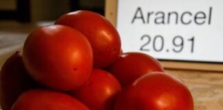 Photo illustration with Mexican tomatoes in a pile next to a sign listing a tariff rate.