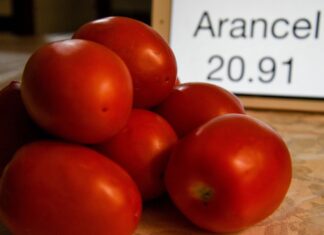 Photo illustration with Mexican tomatoes in a pile next to a sign listing a tariff rate.