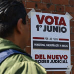 A man looks at a poster reading "Vote June 1 for the new judicial power" in Spanish