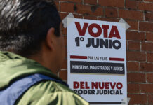 A man looks at a poster reading "Vote June 1 for the new judicial power" in Spanish